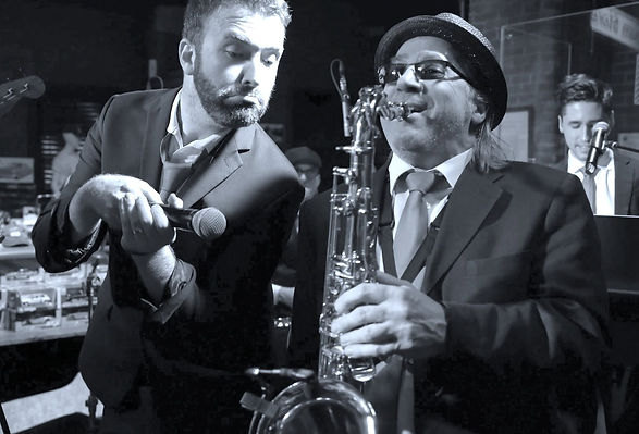 Jazz musician playing saxophone beside vocal performer