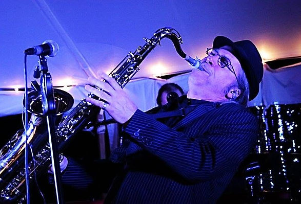Musician performing with saxophone under blue lighting