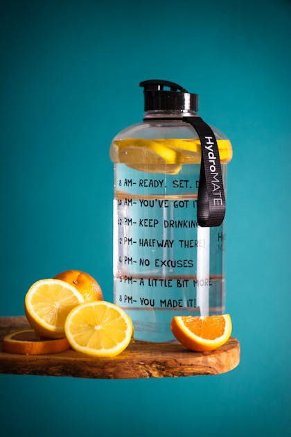 A bottle of water with encouraging text on it , with slices of lemons inside and around the bottle
