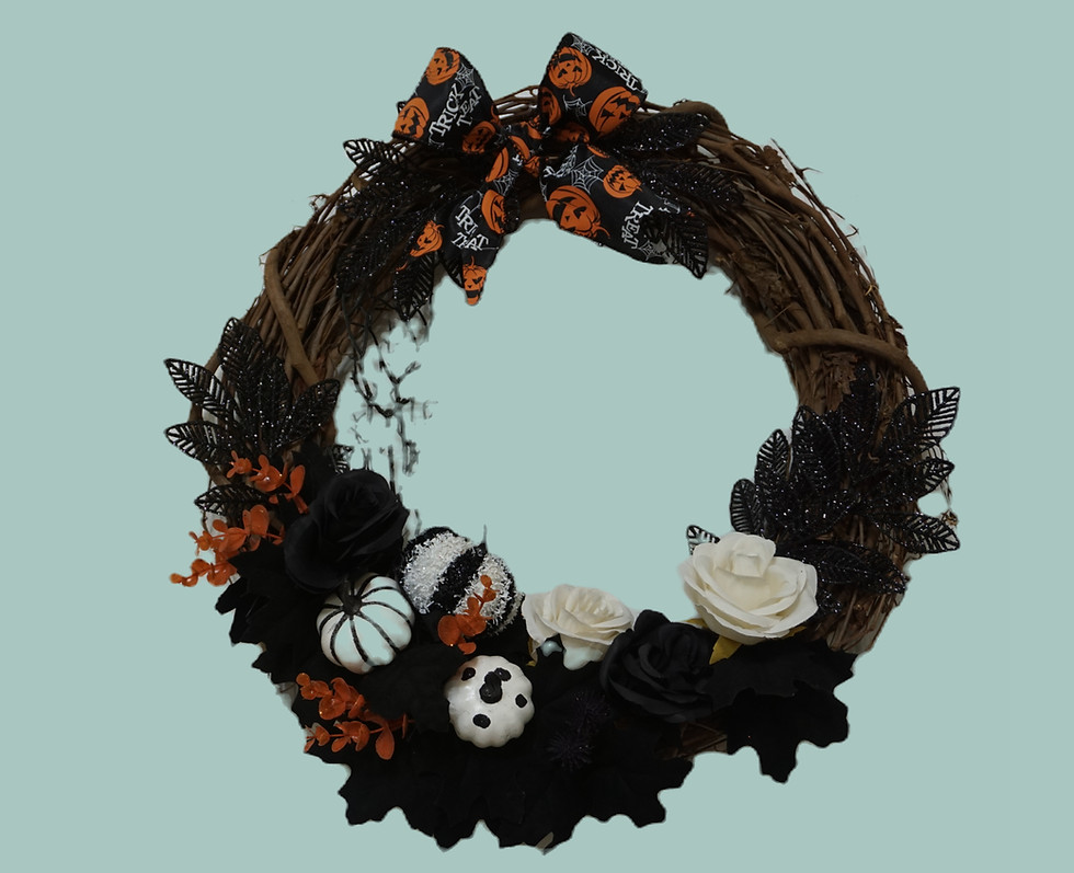 24" grapevine wreath decorated in black and orange florals. There are white and black pumpkins and black roses at the bottom.