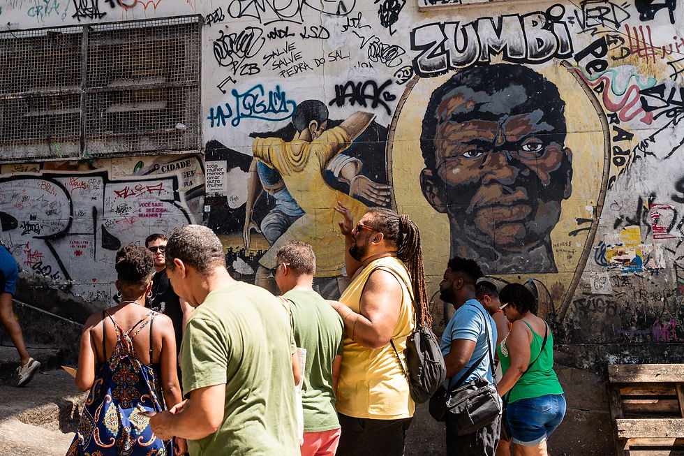 Grupo de pessoas negras caminha pela Pequena África em frente a mural de Zumbi localizado na Pedra do Sal.