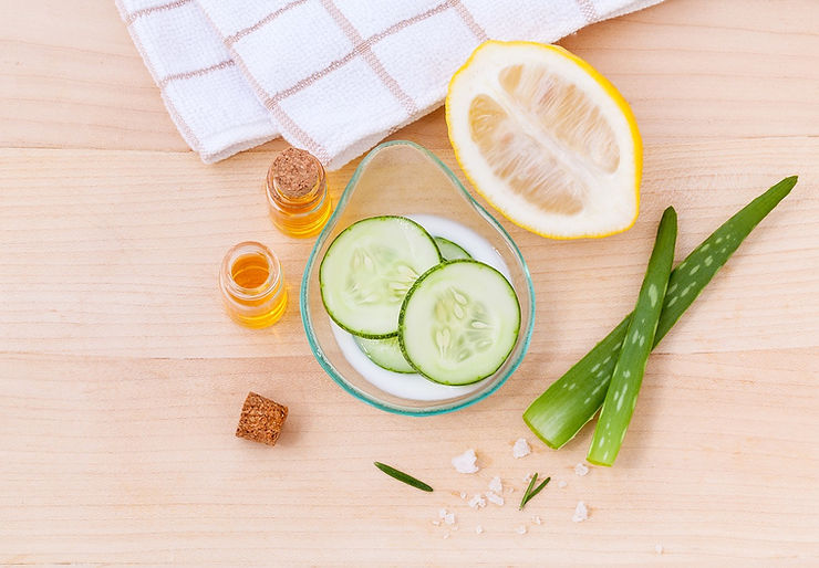 A table full of cucumbers, honey, lemons, and aloe vera.