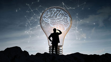 Silhouette di un uomo davanti a una grande lampadina accesa che racchiude un cervello luminoso e reti di connessioni.