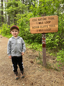 Little boy standing next to trailhead sign for Indian Cliffs Trail in Heyburn State Park.
