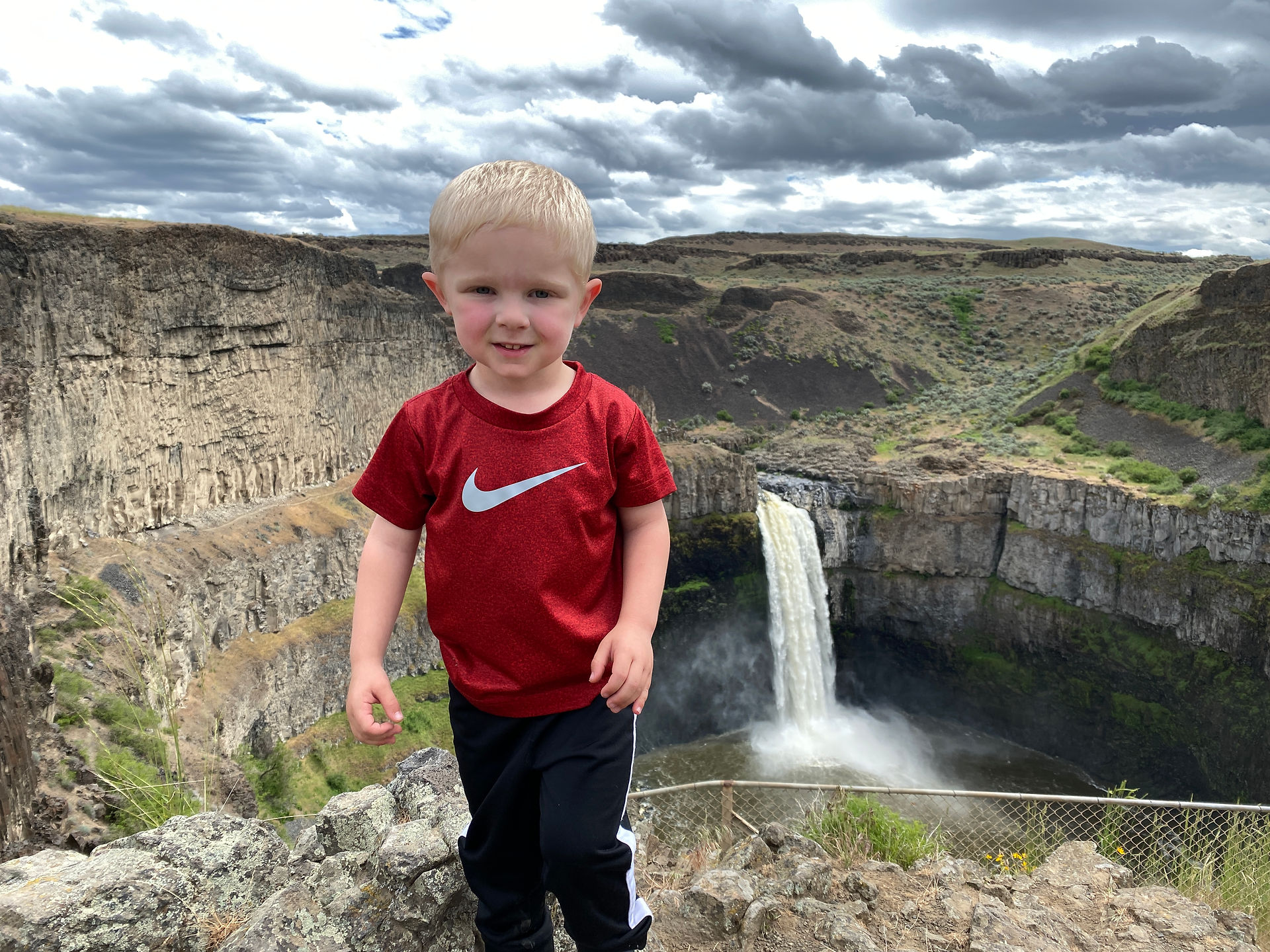 Little boy standing with Palouse Falls in the background.