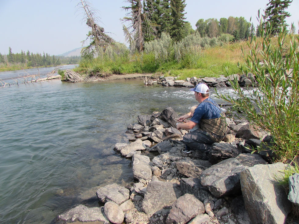 Father and son fishing along the rocky shoreline of the Snake River.