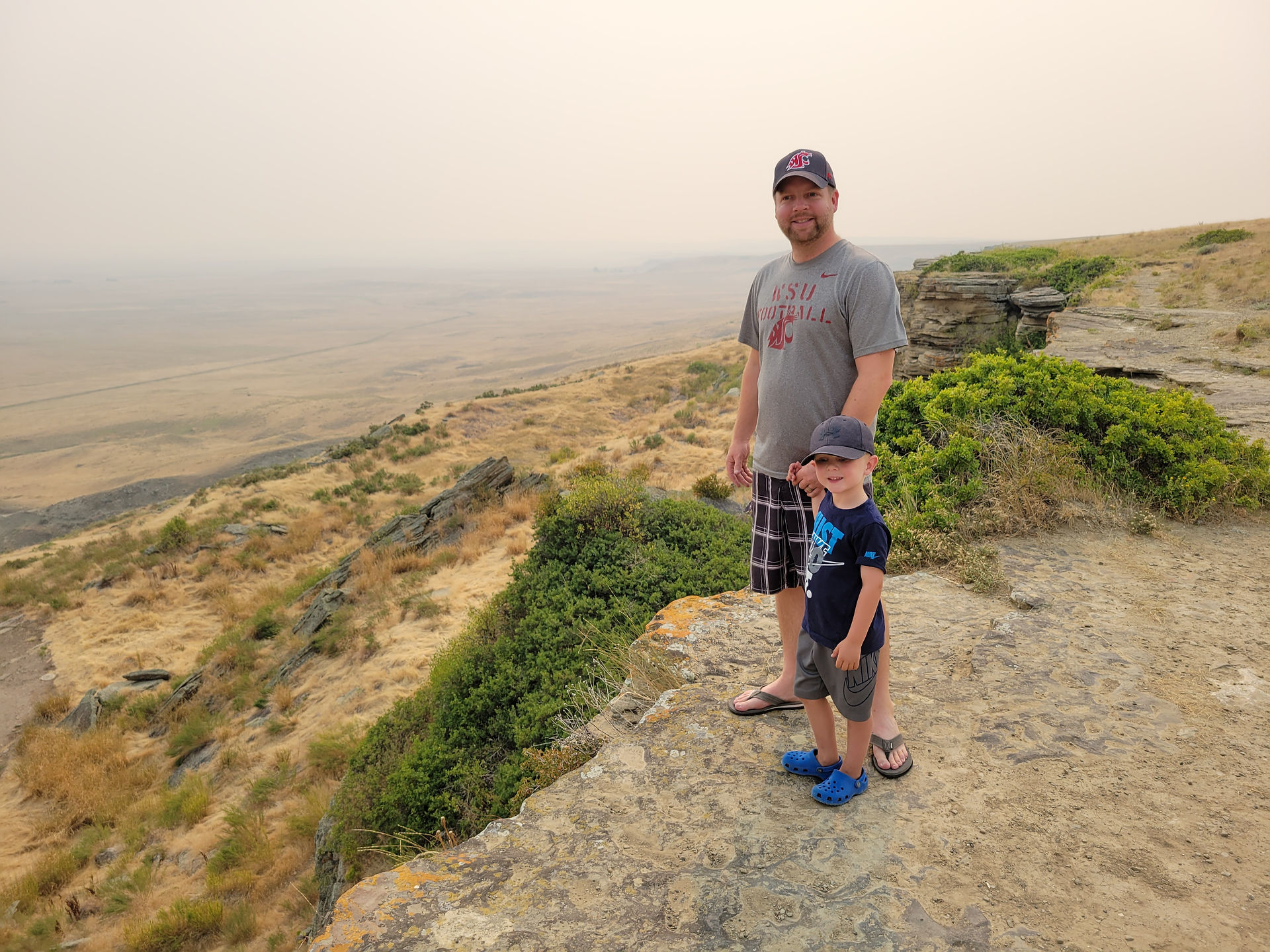 Father and son standing along the cliff edges of the buffalo jump at First People's Buffalo Jump State Park in Montana.