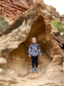 Little boy standing inside a fun hollowed out rock along the Grand Wash Trail in Capitol Reef National Park.
