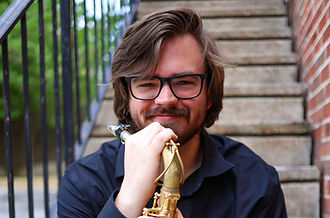 Picture of Harrison Rook sitting on a stairwell holding his saxophone