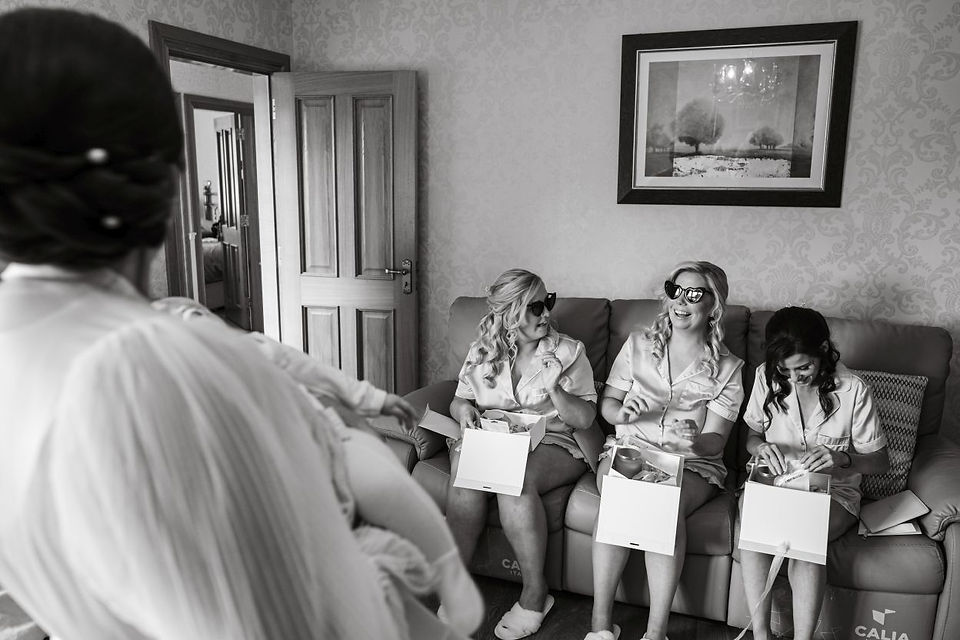 Three bridesmaids open their gifts from the bride