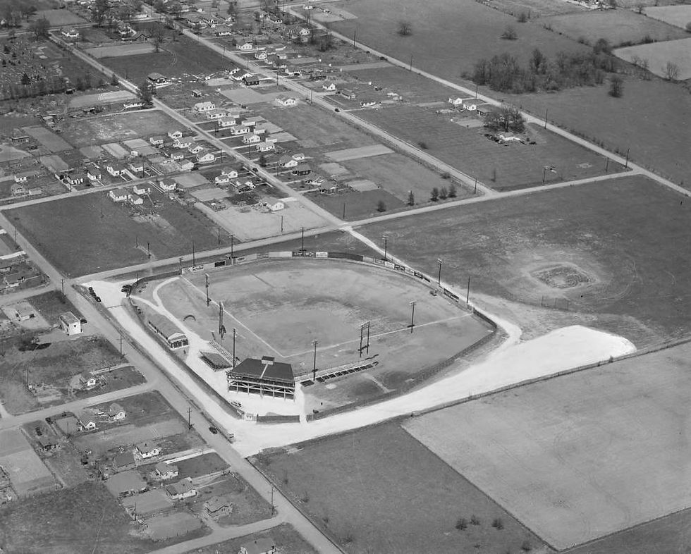 A black and white aerial photograph of Memorial Stadium, a baseball field. Suburban streets and undeveloped lots surround the modest stadium.