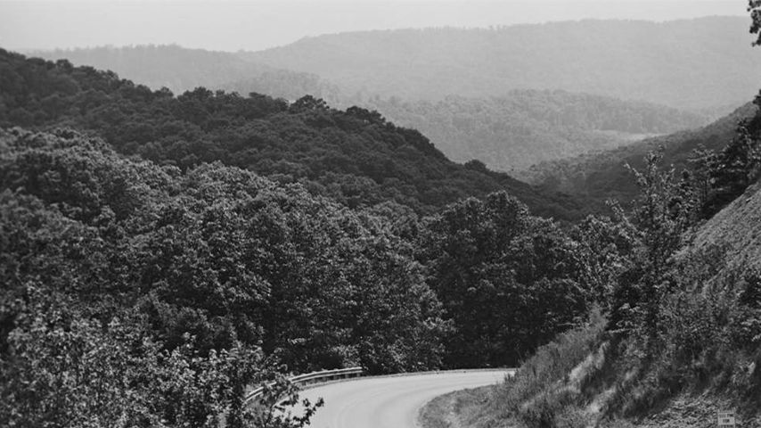 A black and white photograph depicting the rolling peaks of the Boston Mountains in Arkansas.