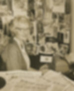 Lucile Morris Upton sitting at her typewriter with newspapers on her desk.