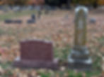 The gravestones of Davis and Lewis Tutt at Maple Park Cemetery. Davis's headstone is newer and constructed of polished granite. Text on Davis's headstone reads: "Davis Tutt. Born 1839 In Yellville Arkansas. Died July 21, 1865 on the public square in Springfield, Missouri." Lewis's monument, an obelisk, is covered in lichen. Text on Lewis's gravestone reads: "Lewis Tutt. Nov 1 1827. Jan. 13. 1900."