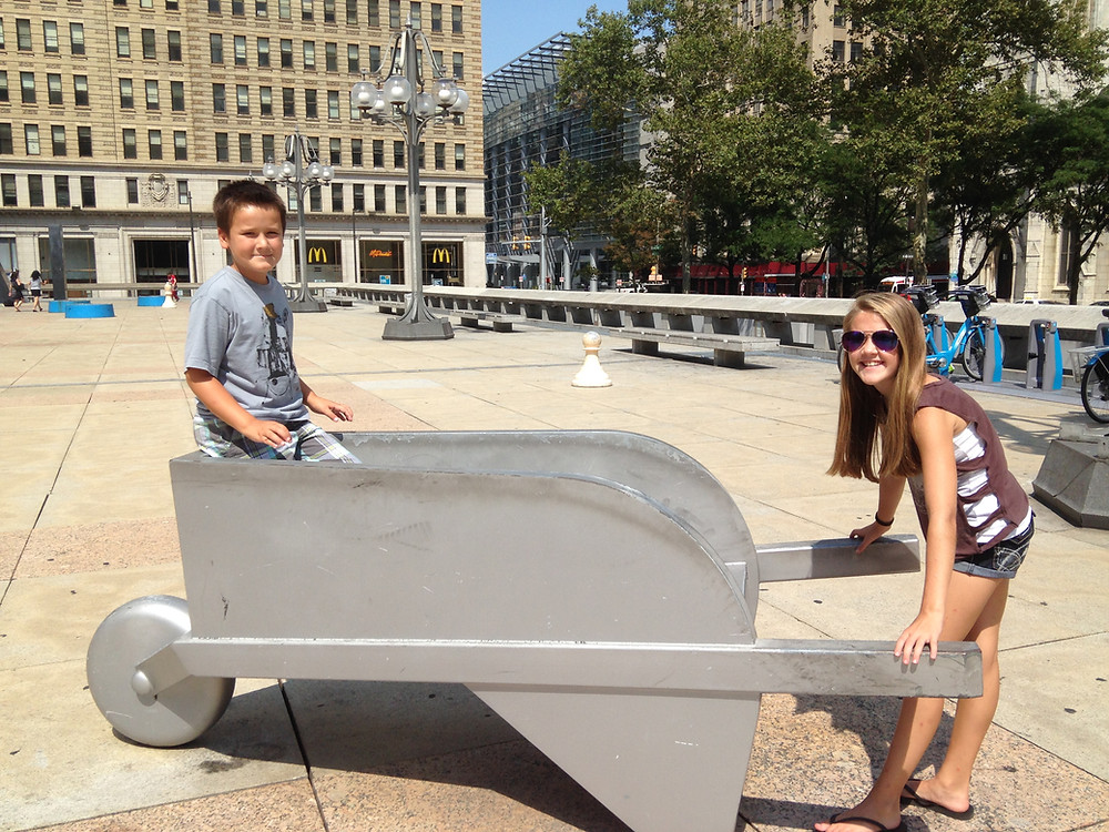 A Girl pushing her brother in a life-sized Monopoly wheelbarrow in Philadelphia.