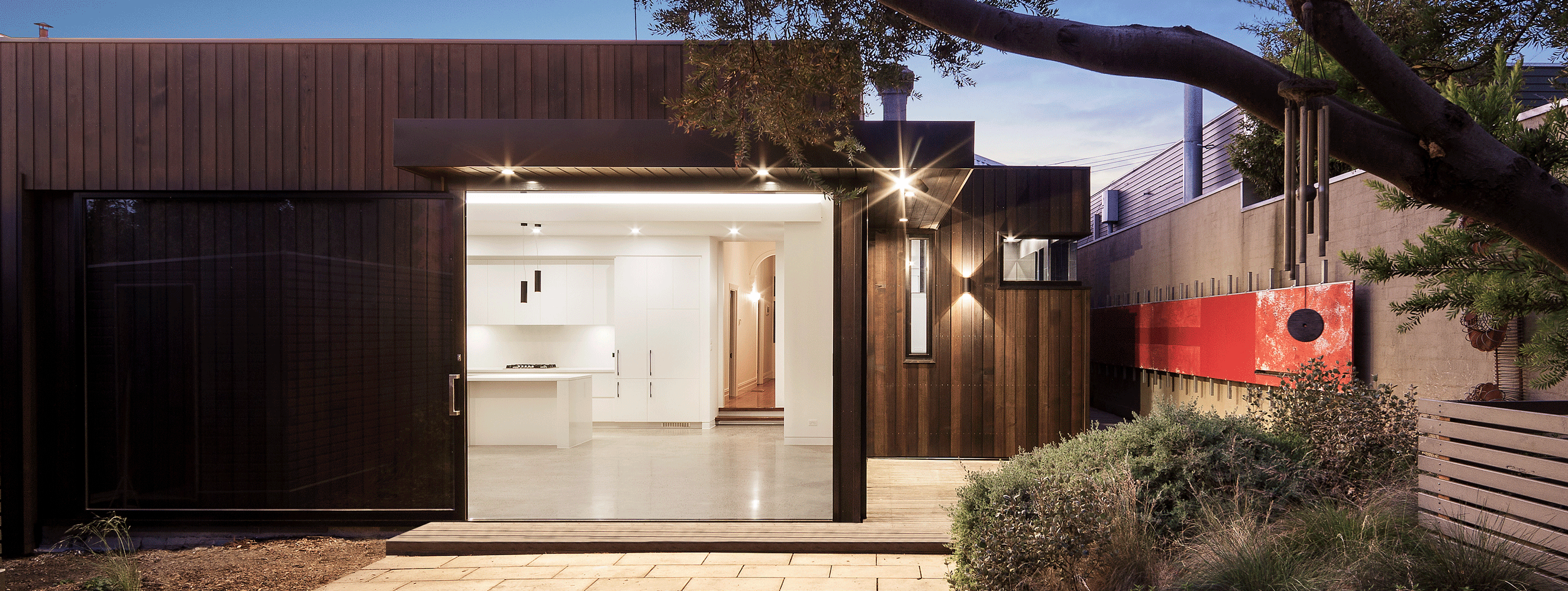 Contemporary Melbourne home featuring dark timber cladding, expansive glazing and a landscaped outdoor living area, designed by Adapt Architecture.