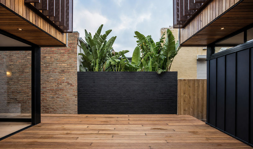 Private central courtyard with timber deck, brick walls and established planting.