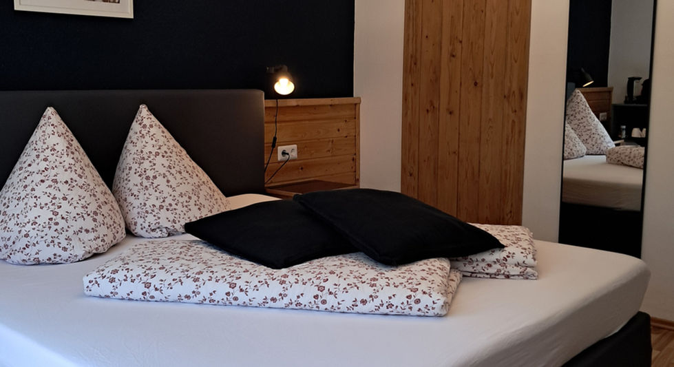 Modernes Doppelbett im Zimmer 3 Maurerbach mit dunkler Wand.
Zimmer mit Frühstück.