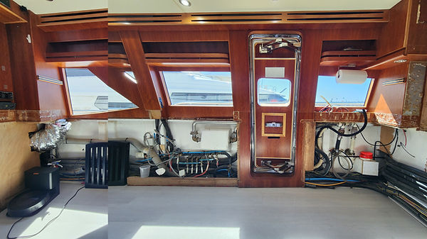 Before renovation: interior of a motor yacht featuring extensive exposed teak wood and plumbing