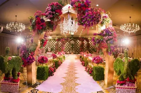 Lavishly decorated wedding aisle with floral arches, chandeliers, and vibrant flower arrangements.
