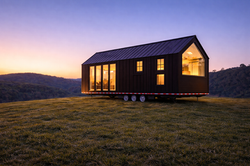 The Bunji tiny house on wheels features a striking dark exterior, pitched roof, and large windows gl