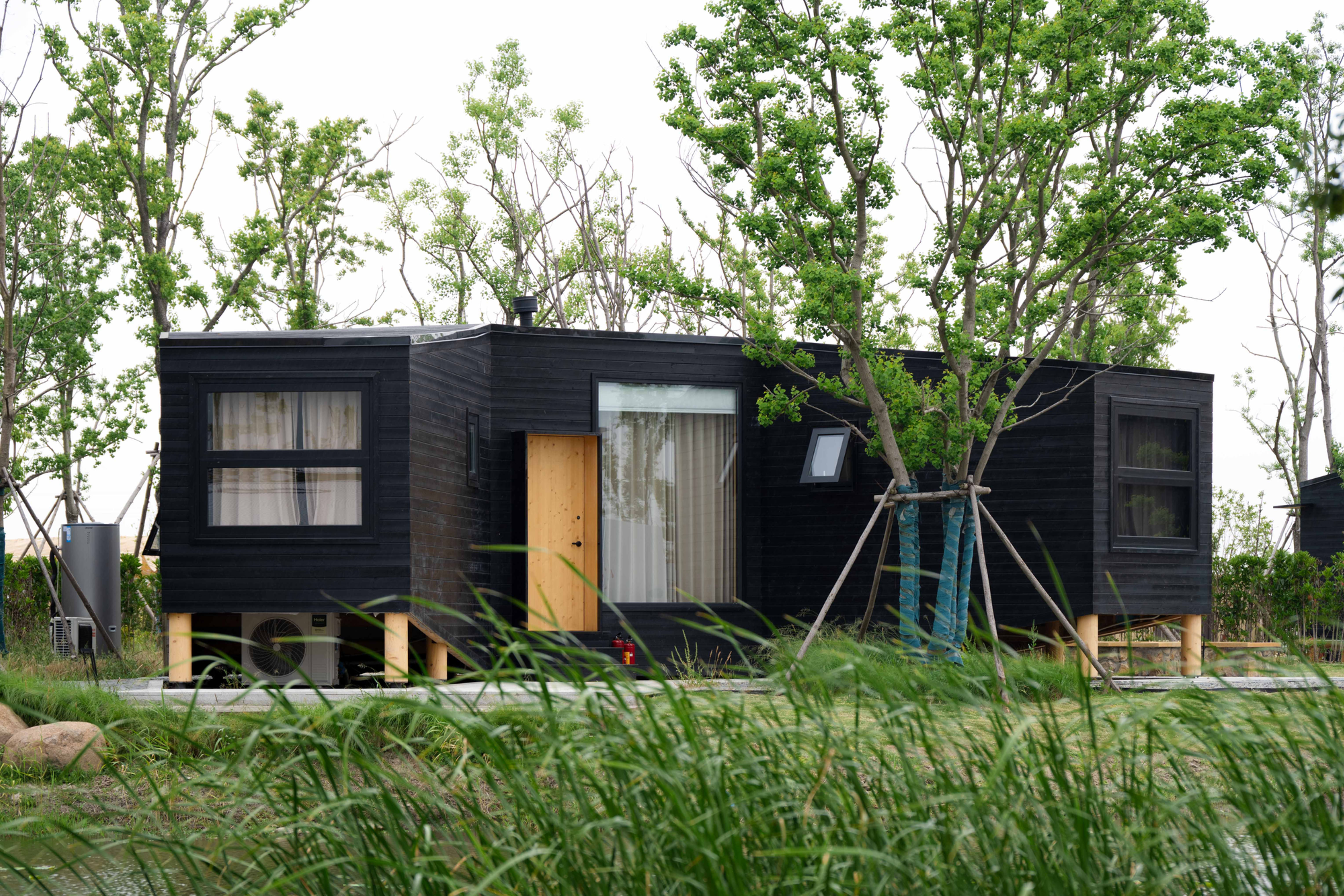 DJARRALY: Dark timber eco cabin exterior with a central entrance and large windows