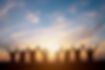 Silhouette of group happy business team making high hands over head in beautiful sunset sk
