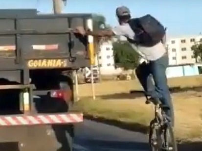 Em pé na bicicleta, homem pega “rabeira” em caminhão; Goiás, vídeo