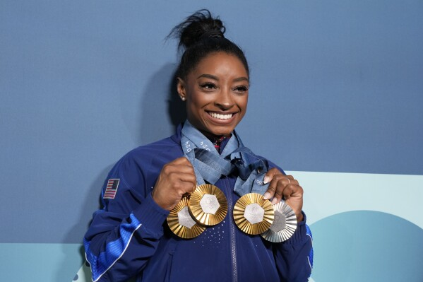 Simone Biles poses with three gold medals and one silver medal following her standout performance at the 2024 Paris Olympics, further cementing her legacy as one of the most decorated gymnasts in Olympic history.