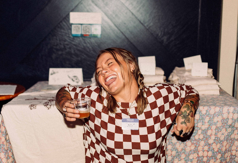 Savs smiling big at the merch table at the ALBATROSS album release party in Nashville, surrounded by merch and album memorabilia.