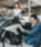 Verkoopster laat motor zien aan man in pak bij motordealer