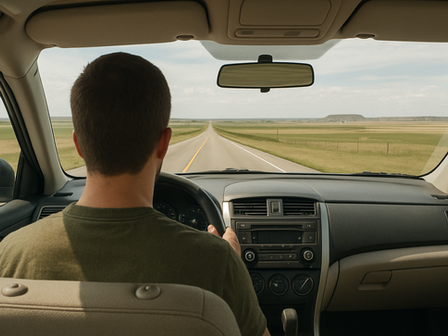 Rear-seat view of driver on open North Dakota highway through windshield