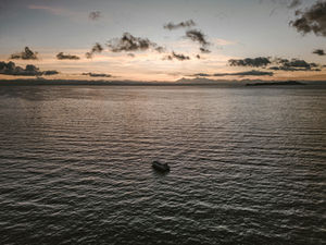 A private luxury yacht navigating the vast, deep blue waters of Lake Titicaca in Peru during a peaceful sunset.