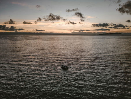 A private luxury yacht navigating the vast, deep blue waters of Lake Titicaca in Peru during a peaceful sunset.