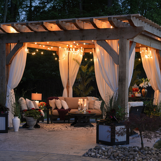 pergola lit up at night with outdoor curtains seating area accessories and decor Design A Rose Interiors Beverly Chicago Create Your Personal Outdoor Oasis