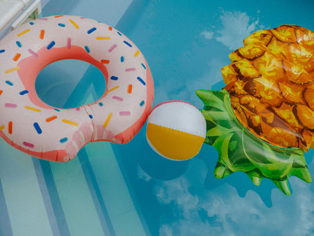 Outdoor swimming pool in the sun and open to evaporation with bright, seasonal pool toys.