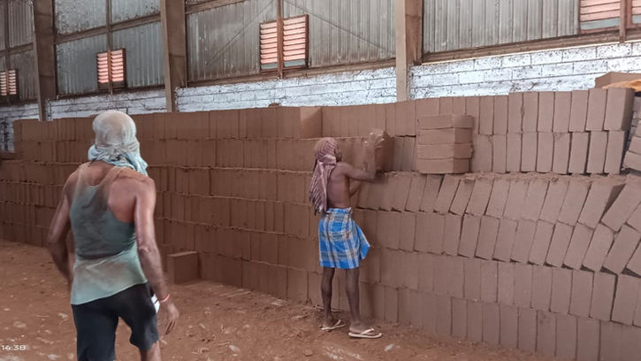 Workers stacking coco peat bricks in a warehouse