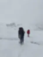 Eye-level view of a trek leader checking cloudy mountain conditions beside a trail marker