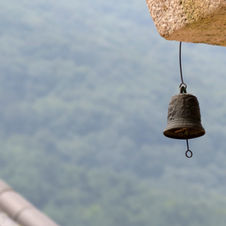 Bronze bell hanging from cliffside