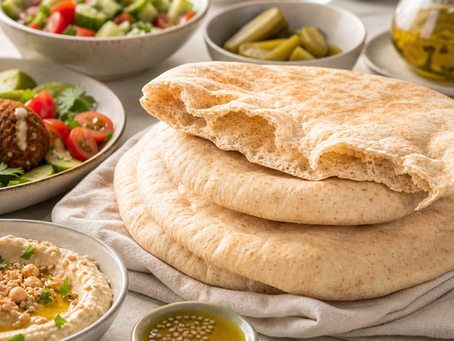 Warm pita bread with hummus, falafel, salad, pickles, olive oil, and tahini, showing pita's healthy roots as part of a balanced Falafel Brothers meal.