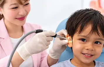 Young boy smiling during gentle microsuction ear wax removal as Brighter Ears Audiologist Vi Bui performs the procedure