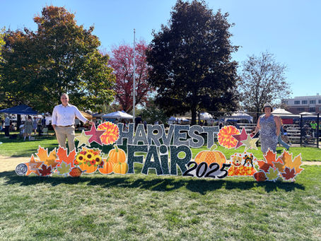 State Rep Josh Tarsky and Senator Becca Rausch standing near a large sign that reads Harvest Fair 2025