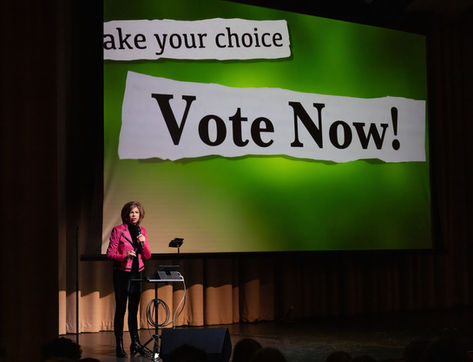 Lyn presenting a screen with the words "Make your choice, vote now!" on the screen.