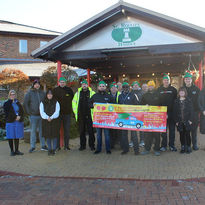 A group of people stand with a large banner for a christmas tree collection for st roccos