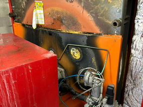 An orange boiler with signs of wear and over heating.
