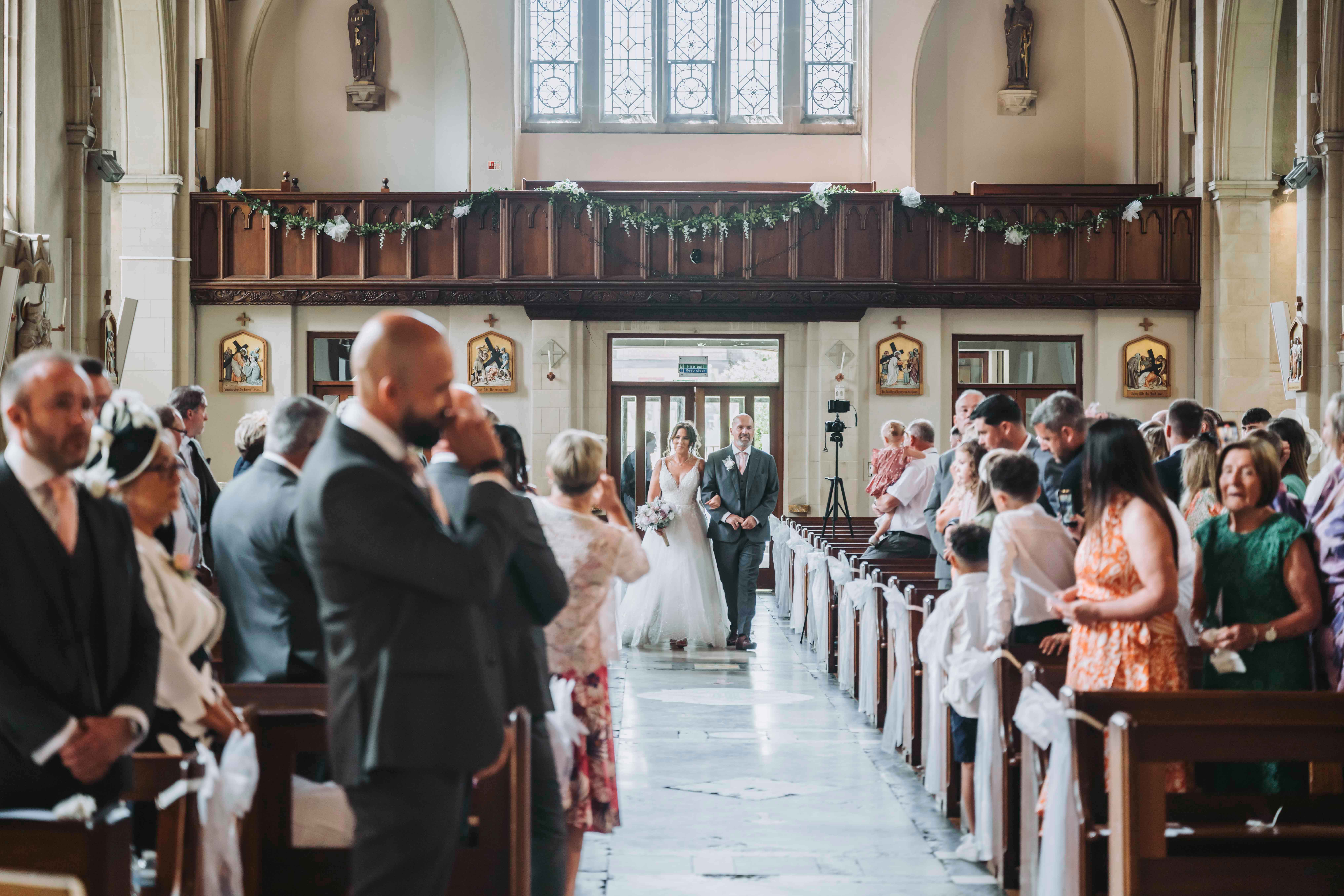 Wedding couple being filmed during their ceremony as they consider a wedding videography package