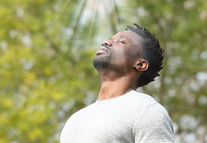 A man arching his back and taking in the rays of the sun.