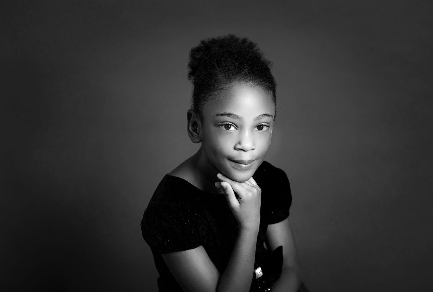 portrait of sweet little girl posing with her hand under her chin.