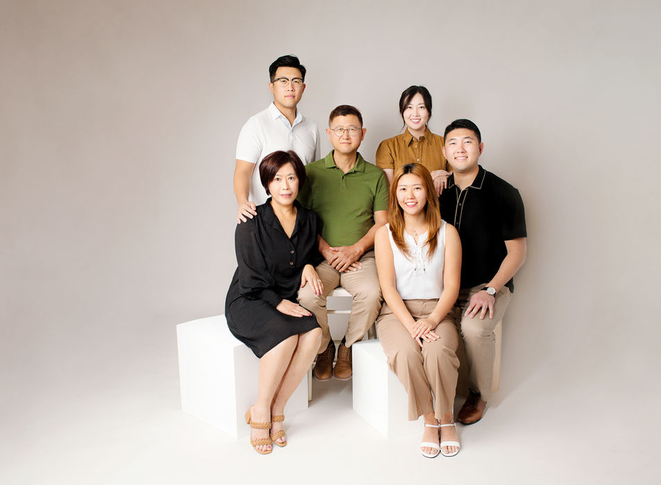 premium portrait studio in Ellicott City, MD captures a beautiful Korean family of 6 sitting on posing blocks in front of neutral taupe backdrop.