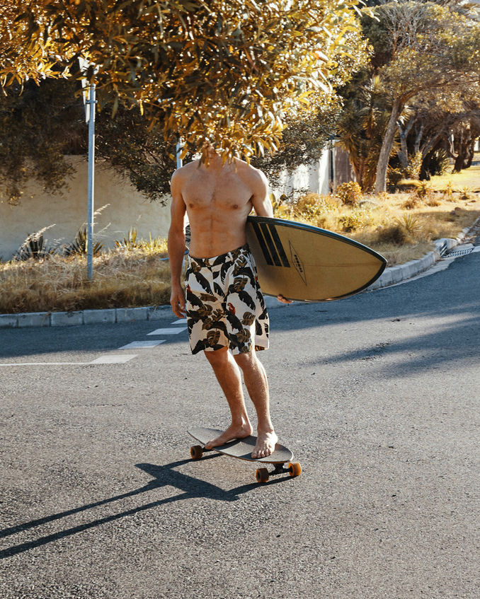 Man carrying surfboard on skateboard